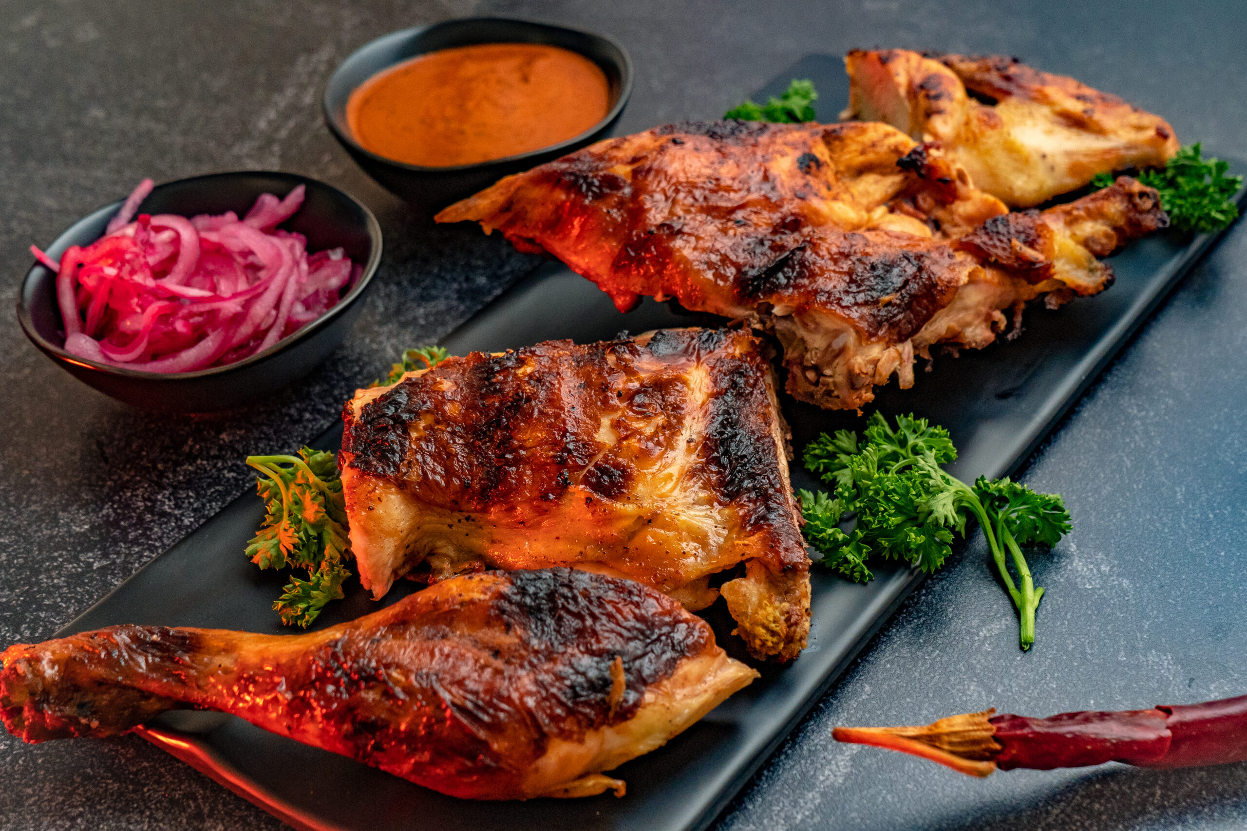 A closeup shot of deliciously prepared chicken served with onions and chili sauce